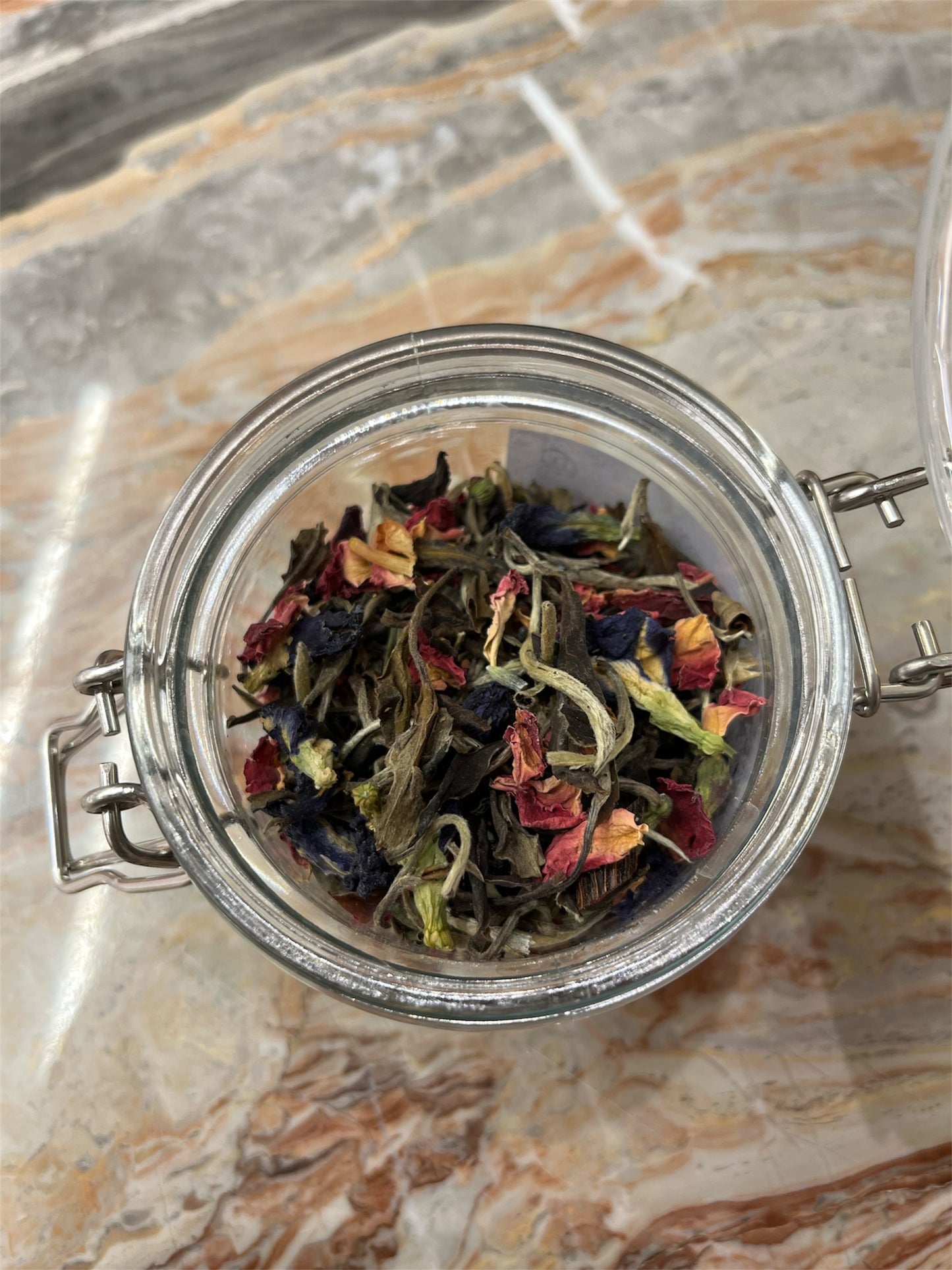 Jar of dried tea leaves on a marble surface