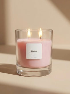 Pink candle in a glass jar with a 'joy' label on a beige background
