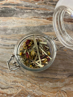 Glass jar with dried herbs on a marble surface