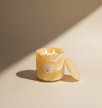 Yellow marbled candle with a lid on a beige background