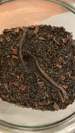 A close-up of loose vanilla black tea leaves in a clear container.