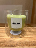 A double-walled glass candle with a wooden lid and a label that reads 'Serenity', featuring a clear wax candle inside.