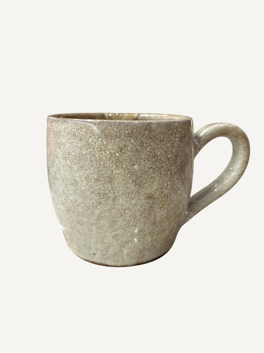 A beige ceramic mug with a handle, displayed against a white background.