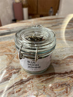 Glass jar labeled 'Blue Moon Jasmine' on a marble surface