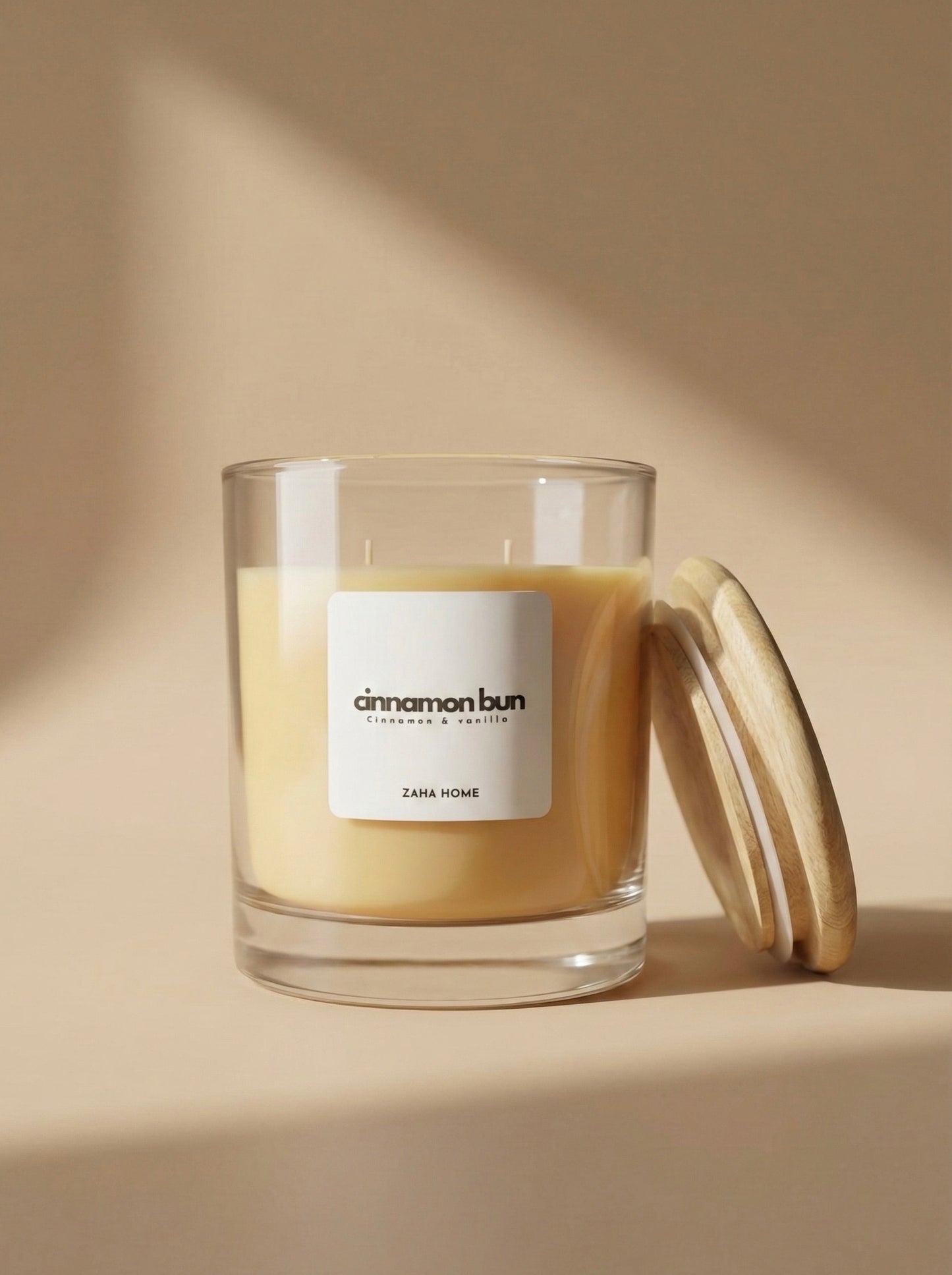 Candle labeled 'cinnamon bun' by Zaha Home on a beige background