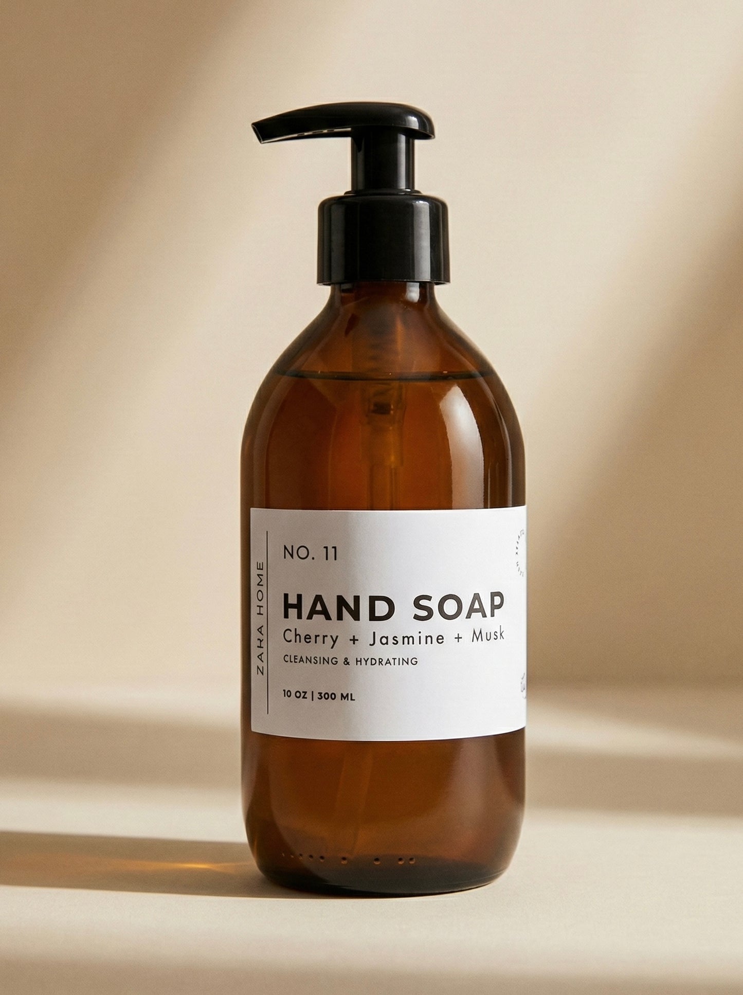 Brown glass hand soap bottle with pump and label on a beige background