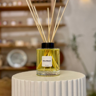 Reed diffuser labeled 'cherry blossom' on a decorative stand with a blurred background
