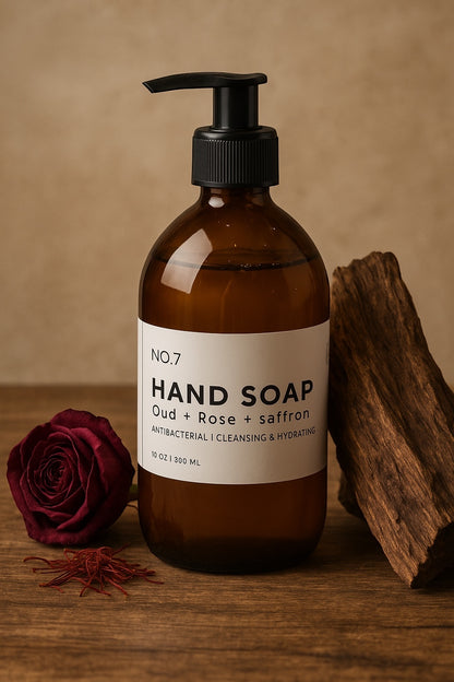 Brown bottle of hand soap with a label, rose, and wood on a wooden surface.