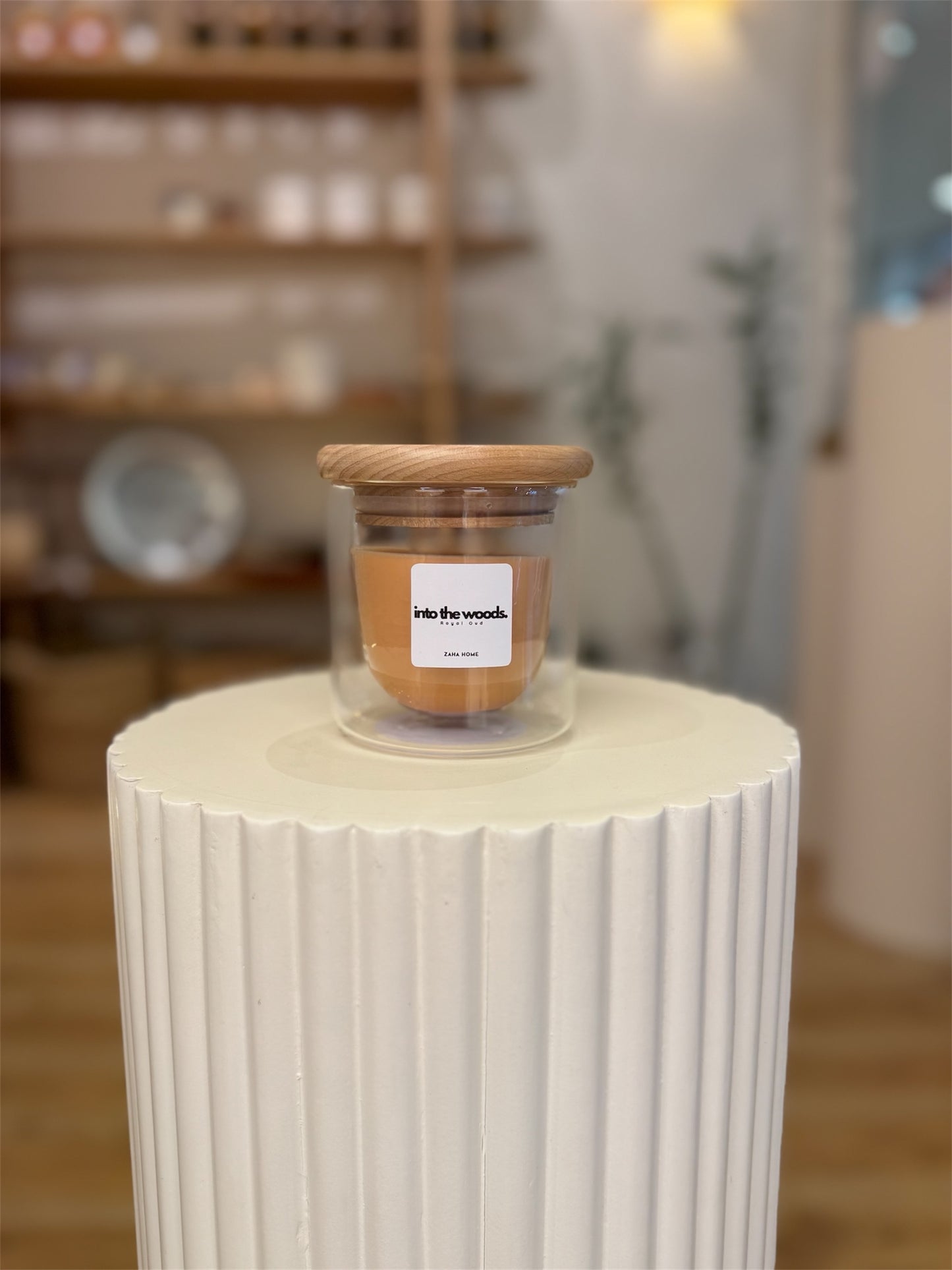 Jar with wooden lid on a white cylindrical surface in a store setting