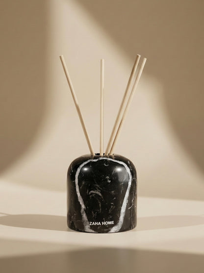 Black marble-patterned diffuser with wooden sticks on a beige background