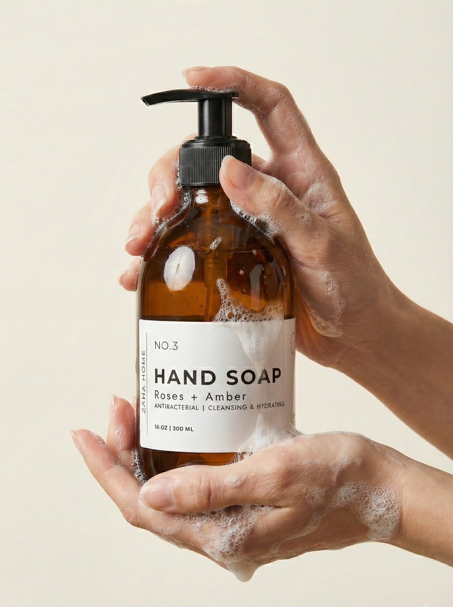 Hand holding a bottle of hand soap with a beige background