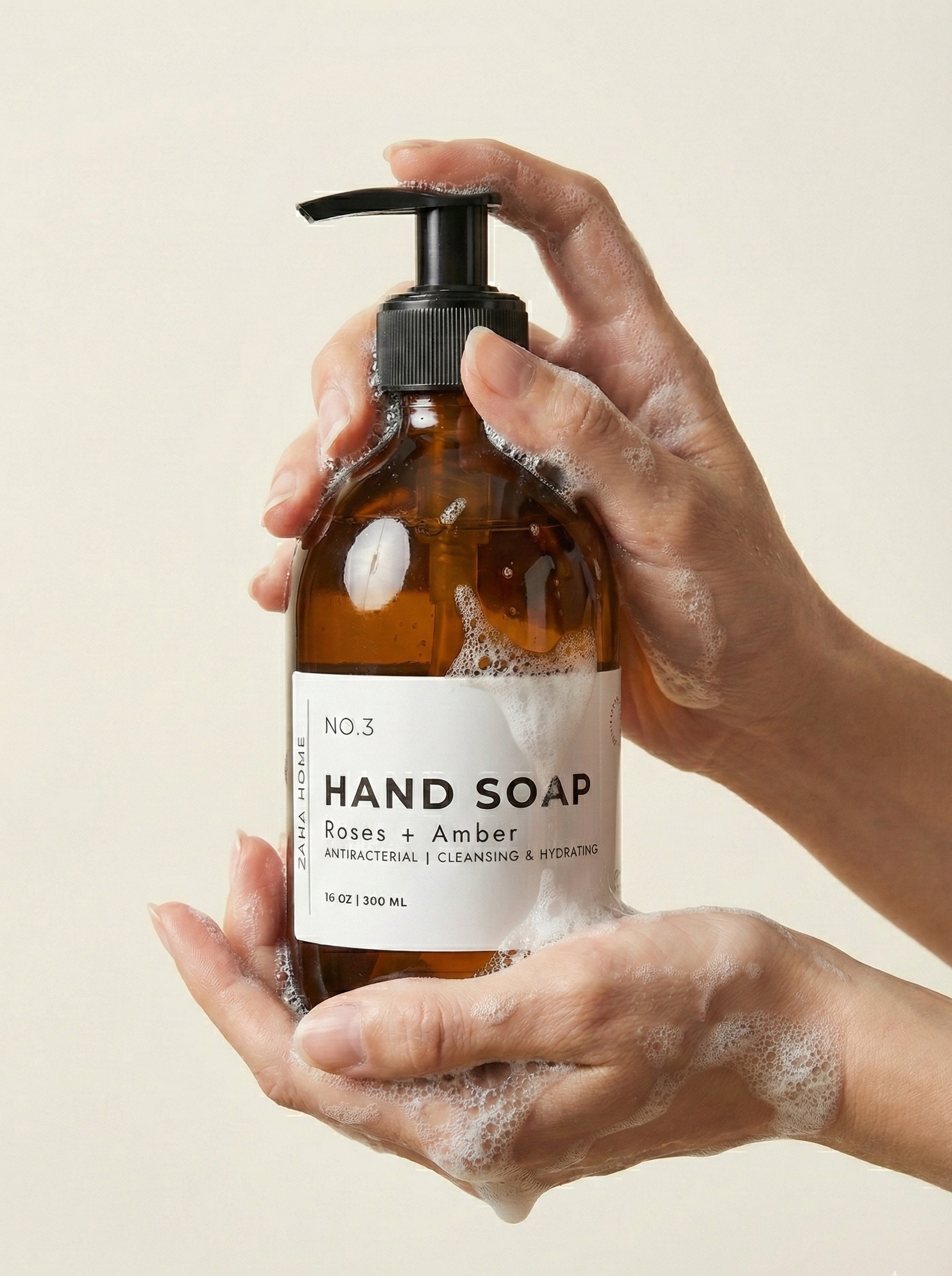 Hand holding a bottle of hand soap with a beige background