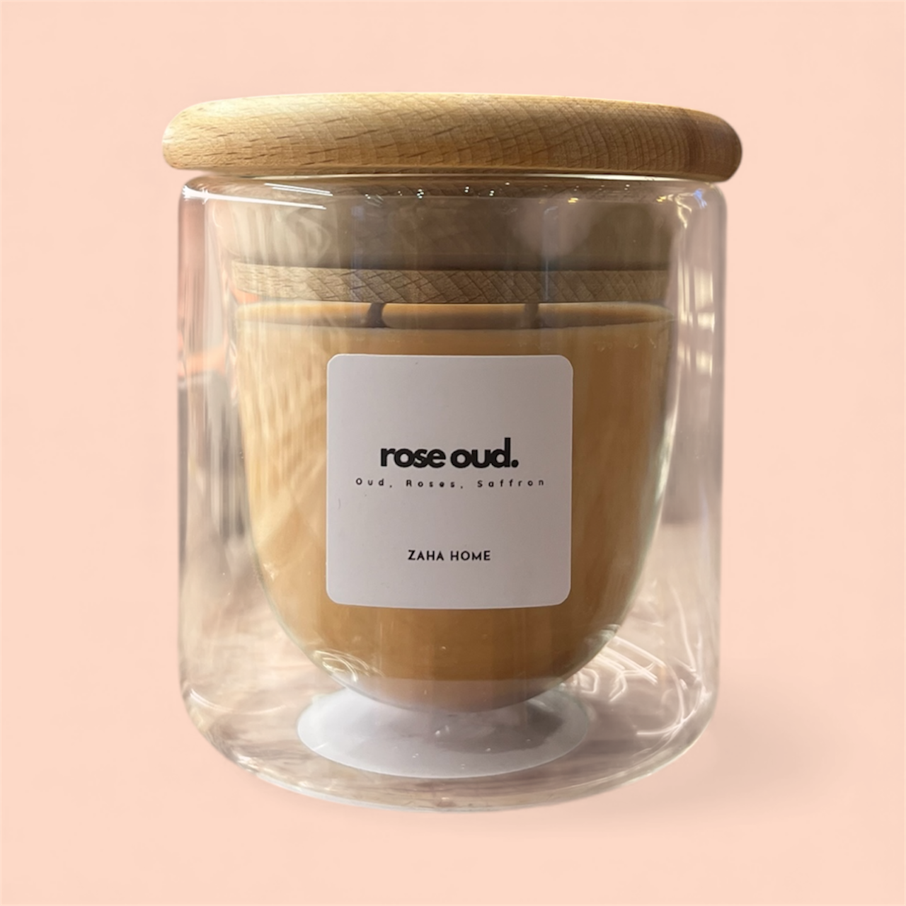 Glass candle with wooden lid and 'rose oud' label on a pink background