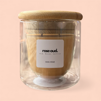 Glass candle with wooden lid and 'rose oud' label on a pink background