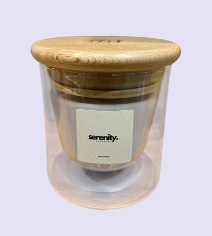 A double-walled glass candle with a wooden lid and a label that reads 'Serenity', featuring a clear wax candle inside.