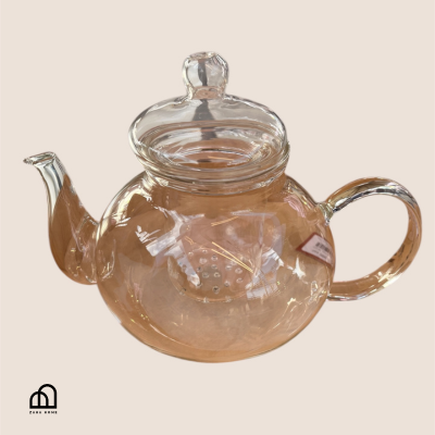 Clear glass teapot with a lid on a beige background