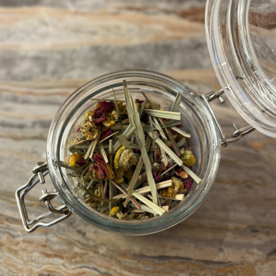 Glass jar with dried herbs on a wooden surface