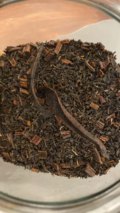 A close-up of loose vanilla black tea leaves in a clear container.