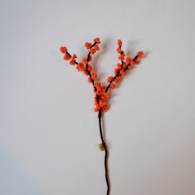 Artificial orange floral branch on a white background